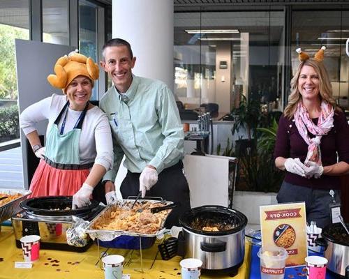 A few volunteers serve cook-off meals while wearing silly hats.